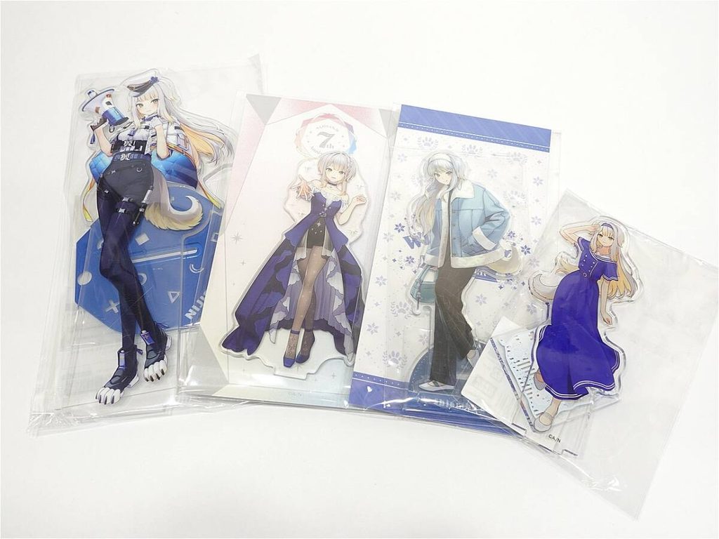 12091444871 1 | Vtuberグッズ買取専門店 Five anime-style acrylic standees in plastic packaging, each featuring a differently dressed female character in blue and purple outfits laid out on a white surface.