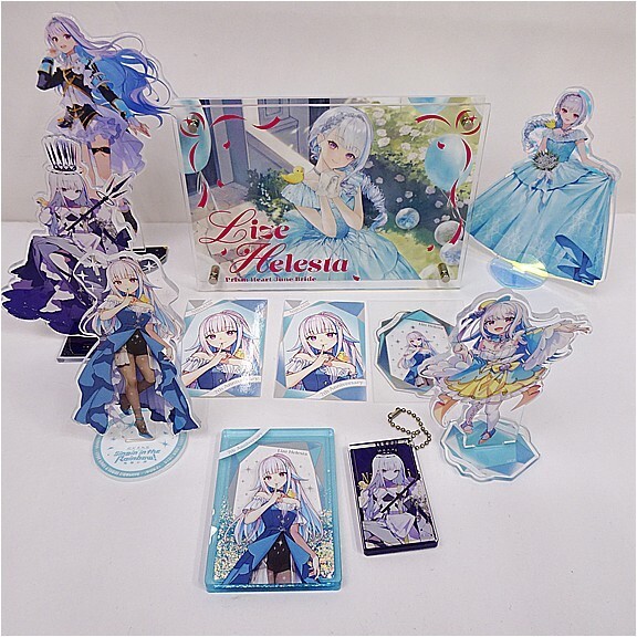 Collection of anime character merch featuring a white-haired girl in a blue dress, with standees, cards, and a display box.