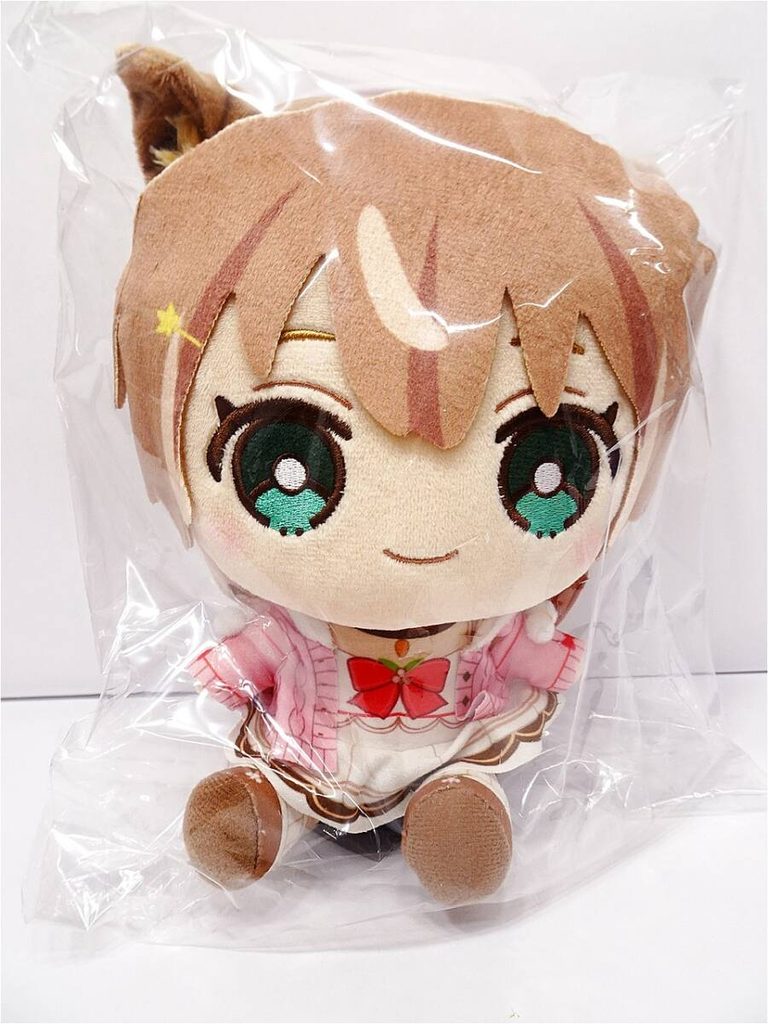 Plush anime character stuffed toy in a clear plastic bag, brown hair, green eyes, wearing a pink cardigan with a red bow.