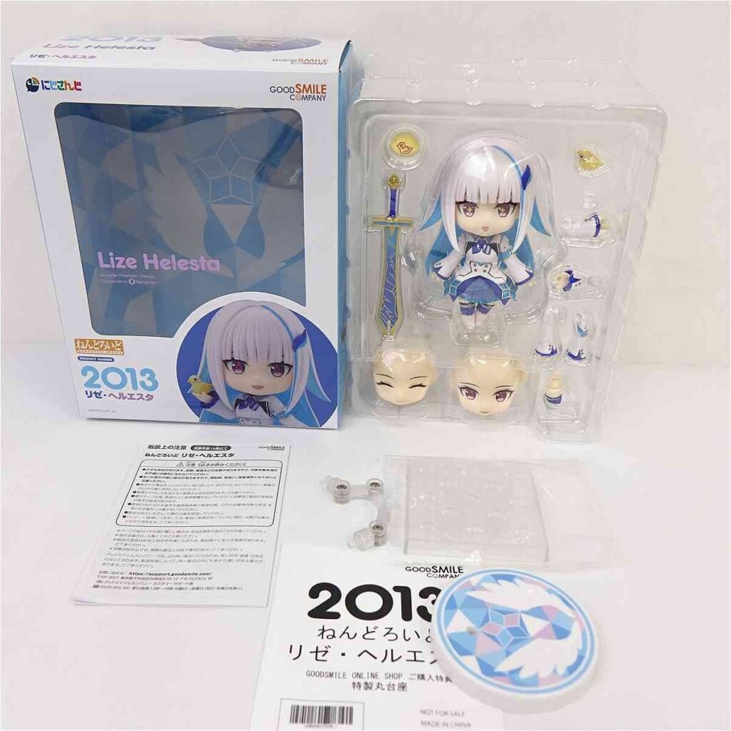 Nendoroid figure of Lize Helesta with sword and accessories in plastic tray beside its packaging box labeled 2013 Good Smile Company/Lize Helesta