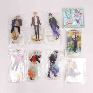 A collection of nine anime character acrylic standees in clear packaging laid out on a light surface, with varied outfits and a colorful card in the top-right corner.