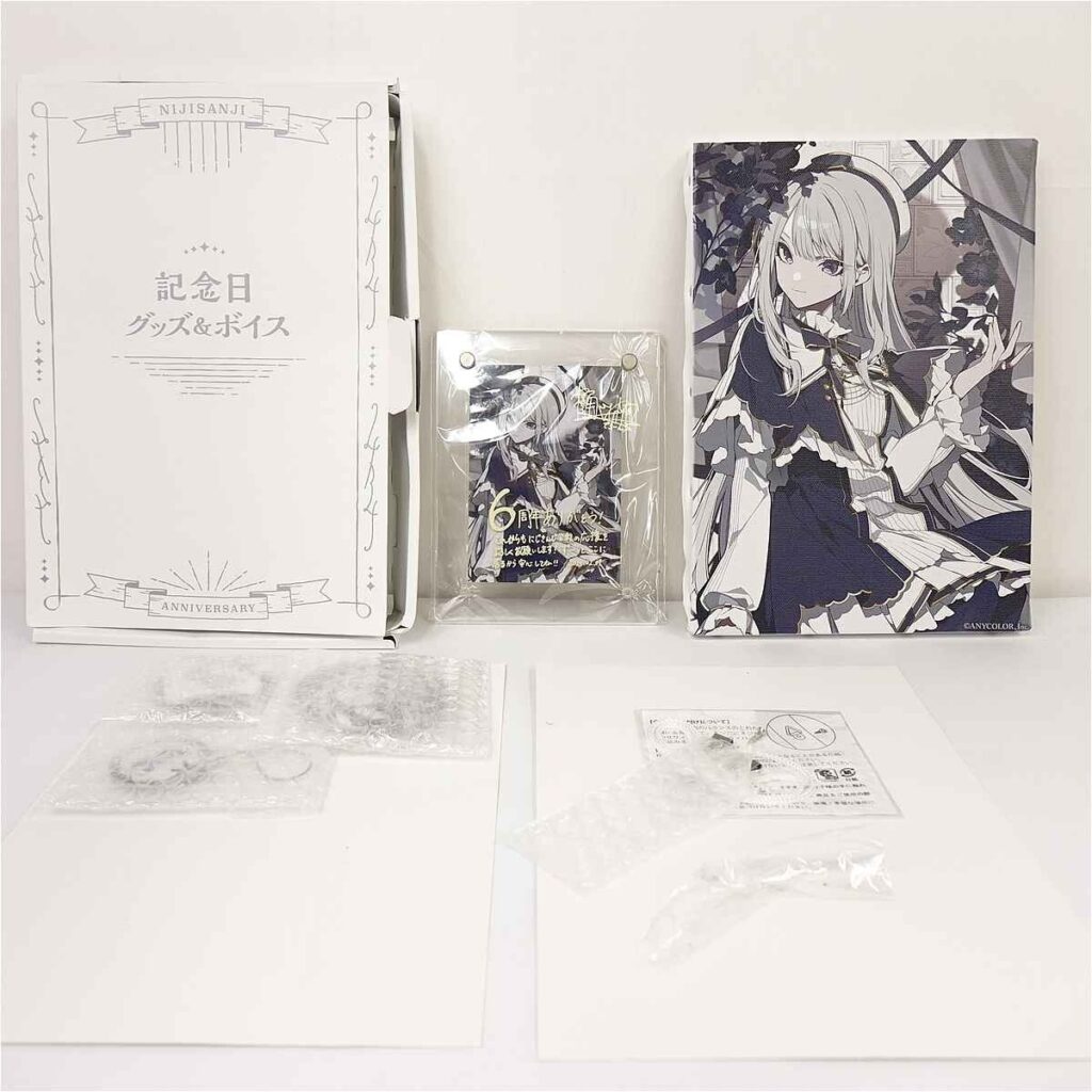 Set of Nijisanji anniversary goods: large white decorative box, a smaller wrapped item, and a tall illustrated box with a girl in a dark dress.
