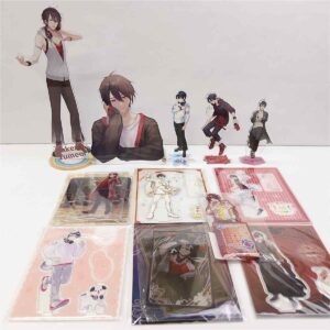 Display of anime character standees and merchandise arranged on a white table: life-size cutouts plus smaller cards and clear files showing various characters.