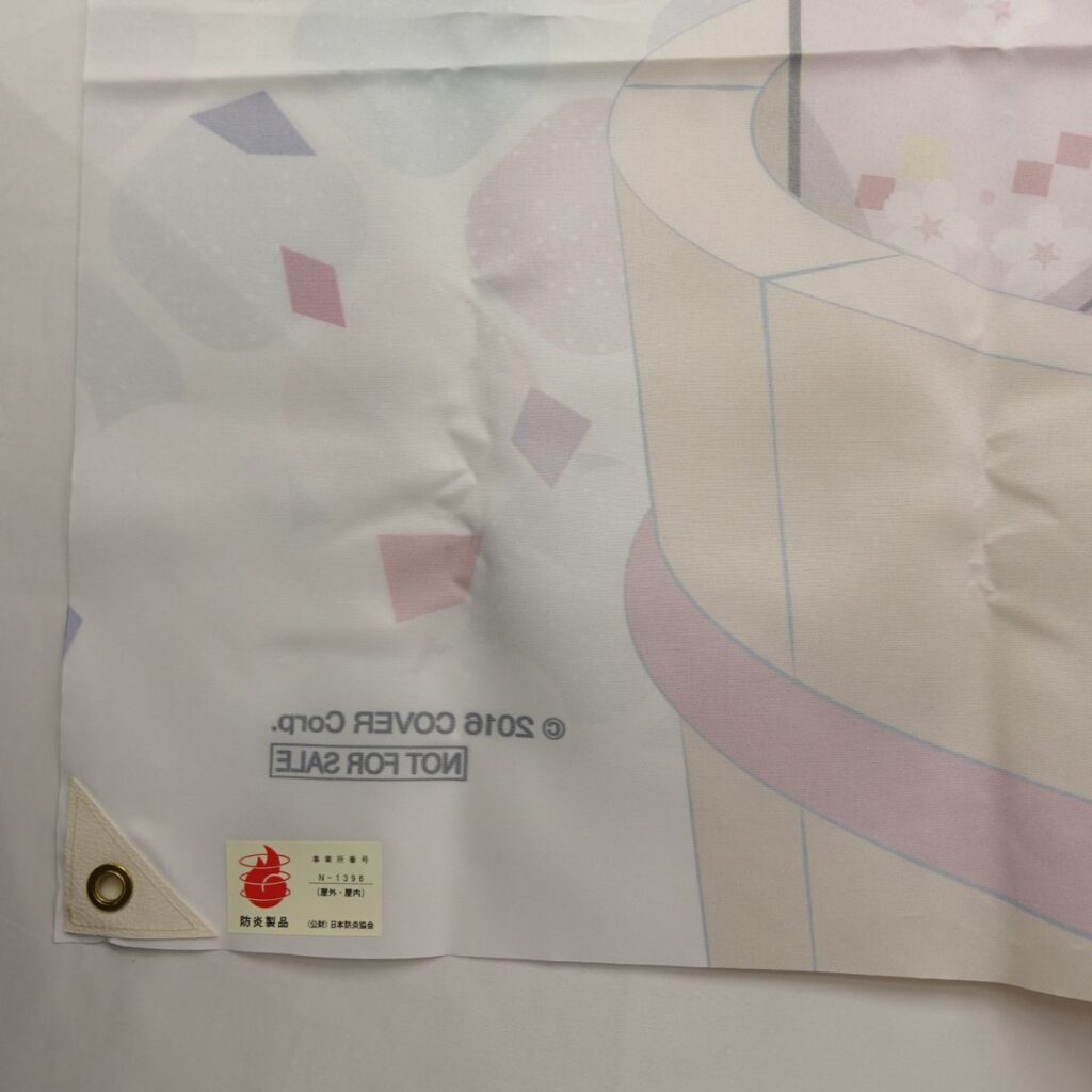 i-img1200x1200-17791038065223hoy3bl36 | Vtuberグッズ買取専門店 Pastel decorative plastic banner edge with corner reinforcement and a metal grommet; small label with red emblem and Japanese text visible.