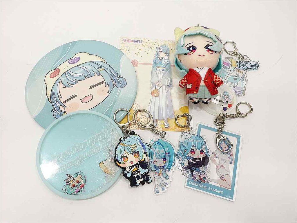 Collection of pastel blue anime merchandise: round plates featuring a chibi character, a plush doll, keychains, acrylic characters, and cards of Shiranami Ramune