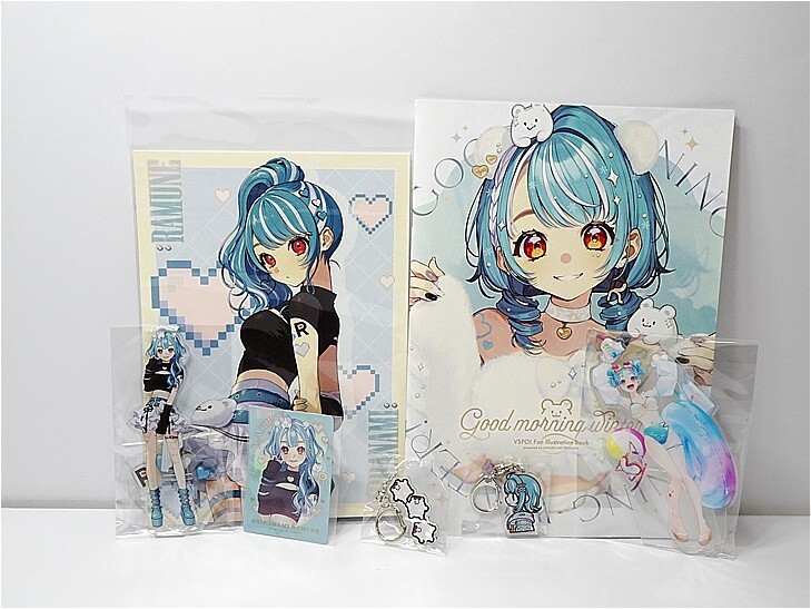Blue-haired anime character merchandise on a white surface: two illustrated posters, several acrylic keychains, and small cards in plastic sleeves.
