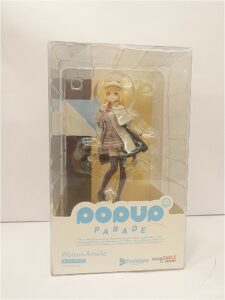 Collectible Pop Up Parade figure of Watson Amelia in clear packaging, standing in a white coat and plaid outfit with blonde hair.