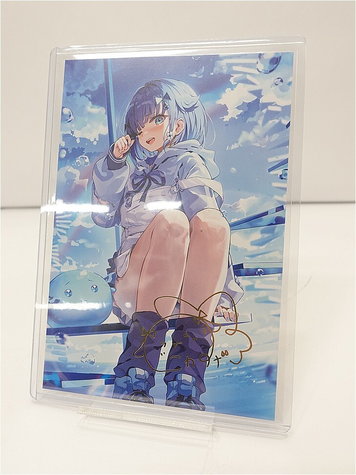 Autographed anime artwork of a girl with blue hair in a gray hoodie, sitting with knees up, against a blue sky.