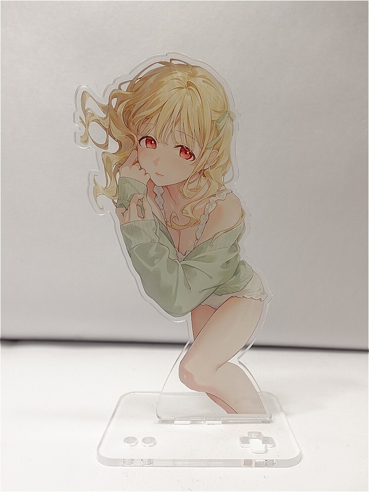 Anime-style acrylic standee of a blonde girl with red eyes, wearing a green cardigan and white frilly shorts, leaning on her hand.