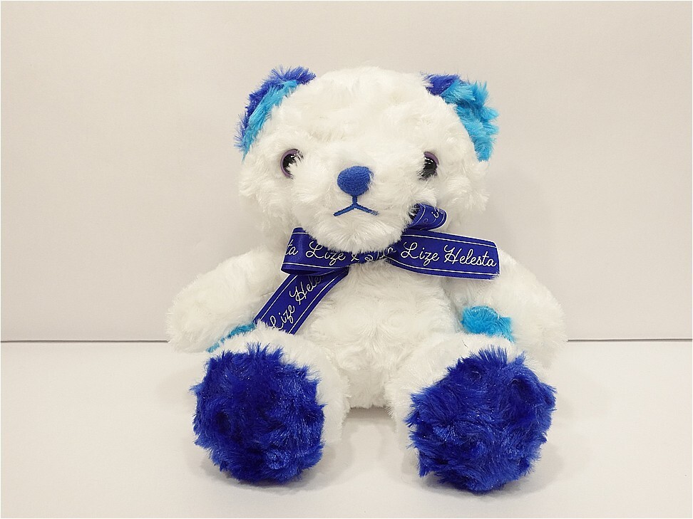 White plush teddy bear with blue paws, nose, ears, and a blue ribbon around its neck