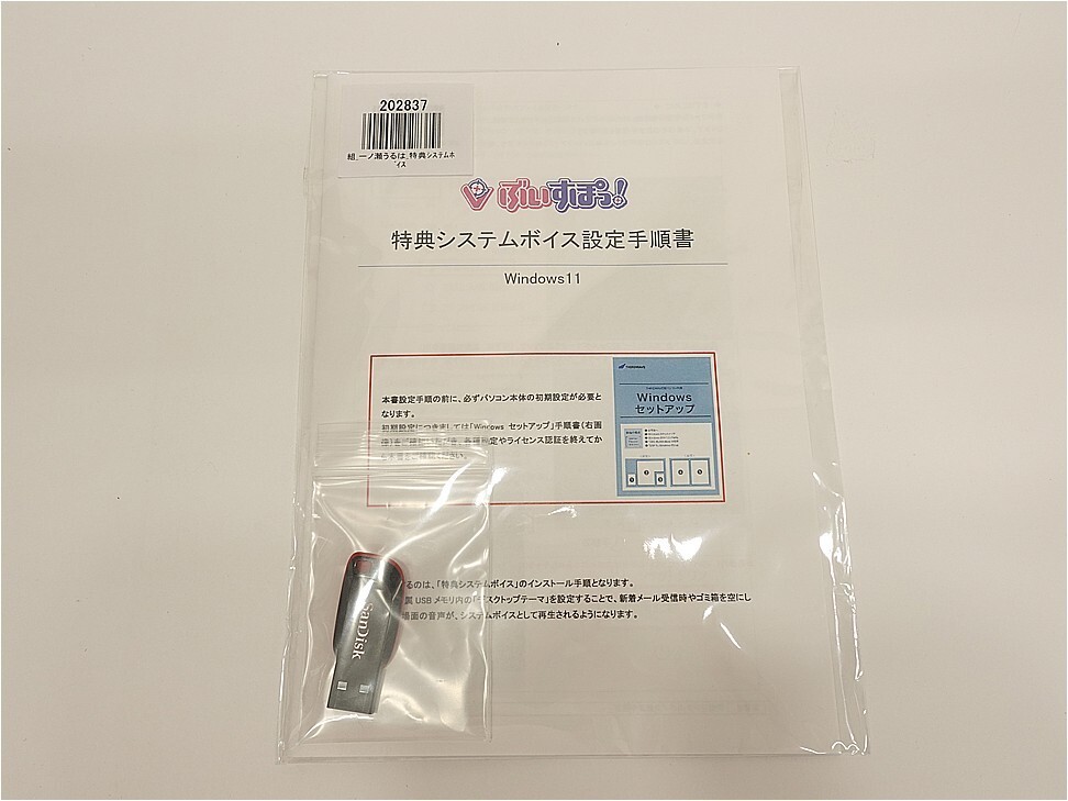 Transparent plastic bag containing a Windows 11 setup manual and a small USB drive. (Japanese text on the manual)