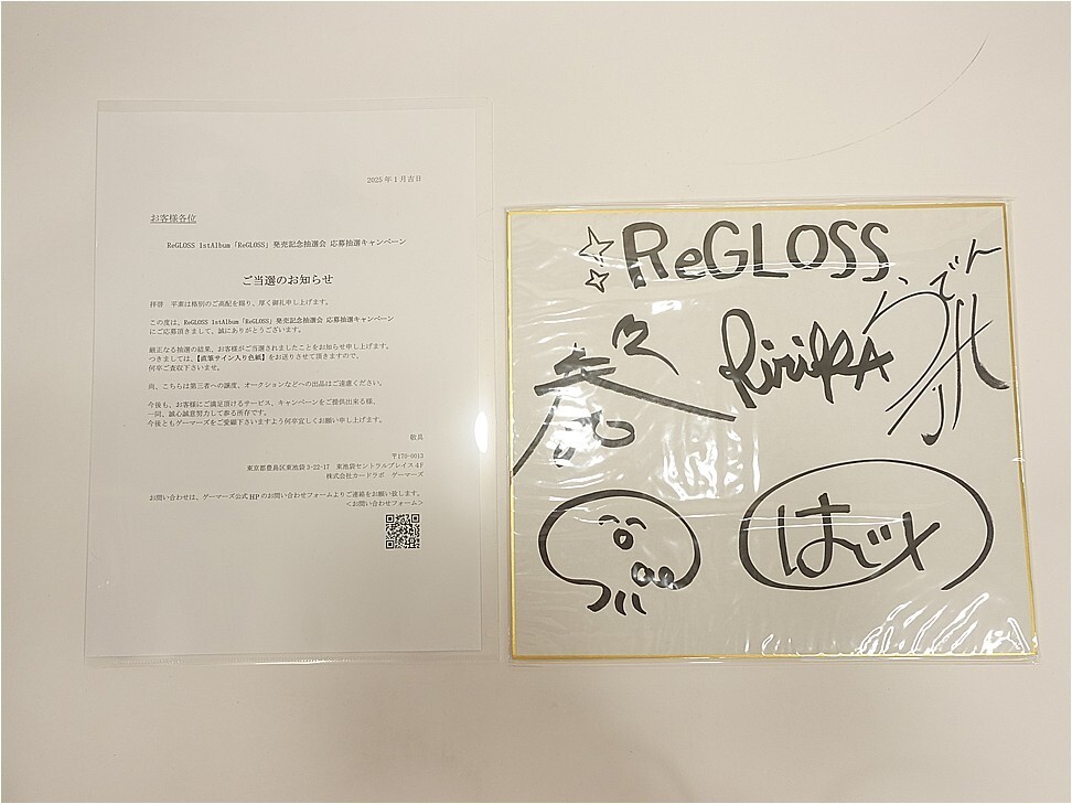 Two framed items on a pale wall: a printed notice on the left and a signed, illustrated poster reading 'RE GLOSS' on the right with doodles and a small face drawing.