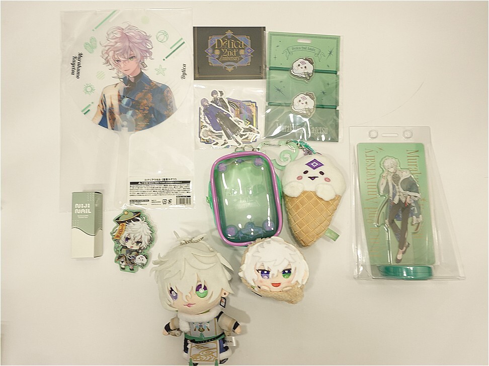 i-img972x729-17742582383499uajipj35 1 | Vtuberグッズ買取専門店 Flat lay of anime merchandise: plushies, stickers, acrylic stands, and a green carrying case on a light background.