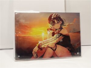 Anime-style girl sitting on the shore at sunset, wearing a black outfit and a checkered cap, gazing toward the viewer.