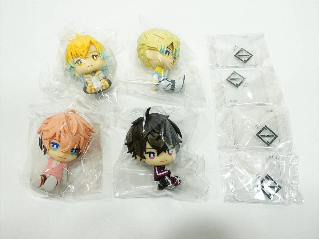 n12117667211 - Vtuberグッズ買取専門店Vtrader Four chibi anime figurines in clear bags arranged on a white surface, with extra small accessories in separate bags on the right side.