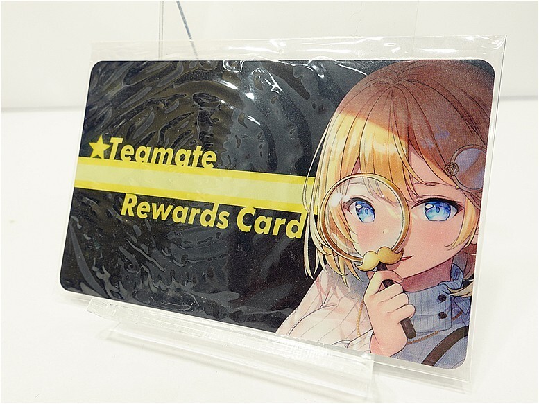 Plastic loyalty card with anime illustration of a blonde girl peering through a magnifying glass and the text 'Teamate Rewards Card' on a black background with yellow lettering.