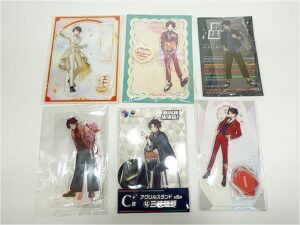 Six packaged anime character standees laid out on a white surface, showing the same male character in different outfits and poses.