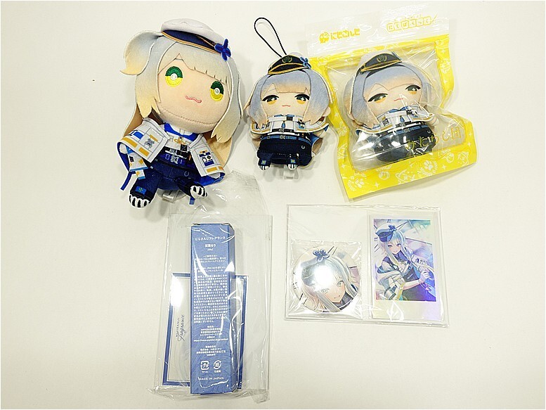 Three anime-style plush keychain figures in blue sailor outfits on a white surface, with packaging and character cards nearby.