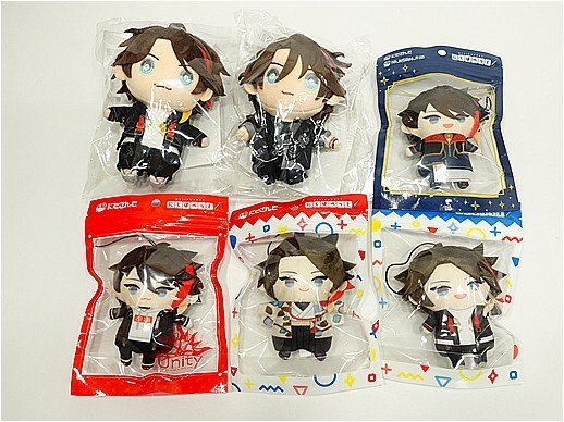 w12144135511 - Vtuberグッズ買取専門店Vtrader Six small chibi plush toys of a brown-haired boy with blue eyes, each in a clear plastic bag with red, white, or blue borders, laid on a white surface.